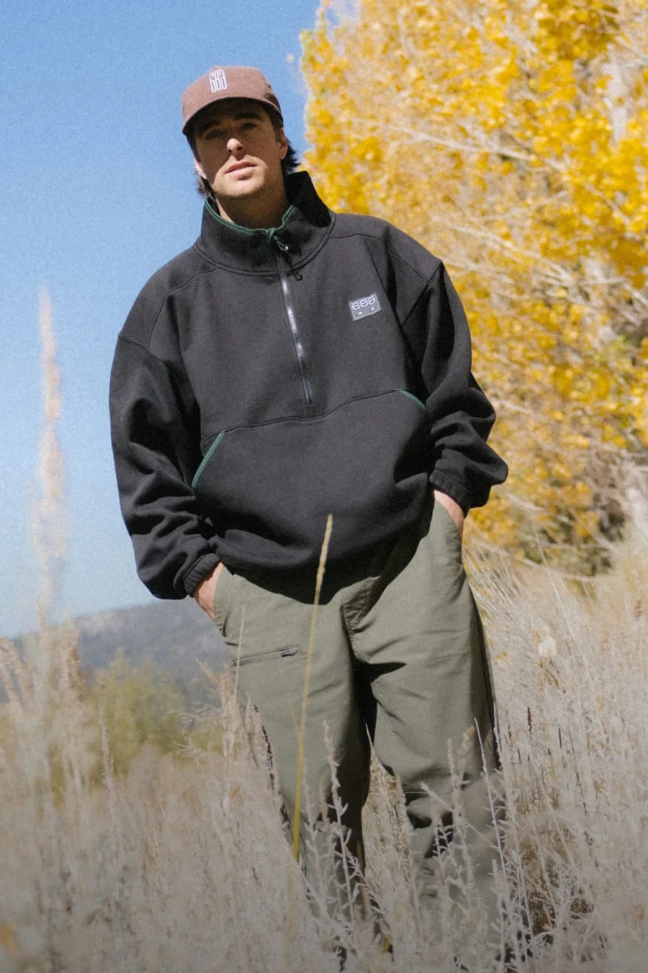 Man in a black 686 fleece pullover walking through tall autumn grass