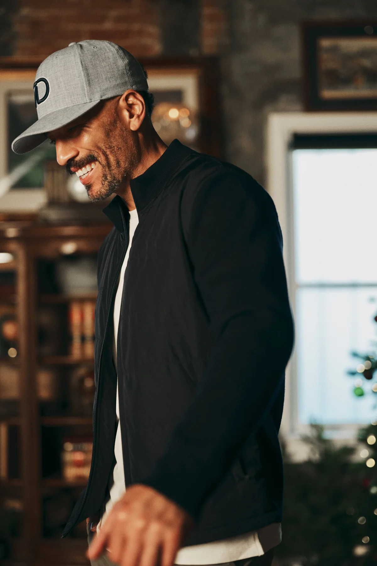 Smiling man in a grey 7Diamonds cap and black jacket in a wood-panelled room