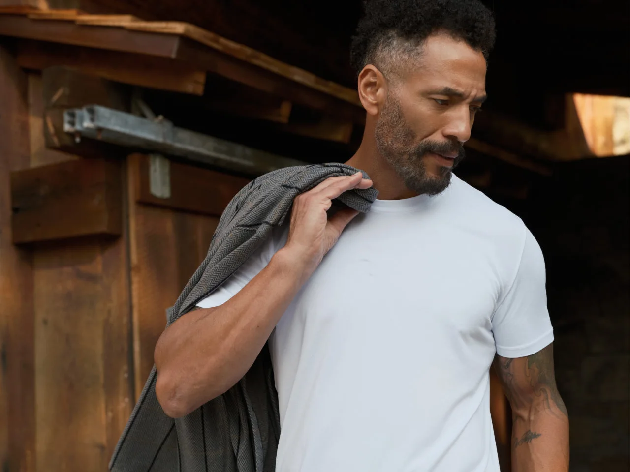 Man in a white 7Diamonds tee with a grey jacket over his shoulder