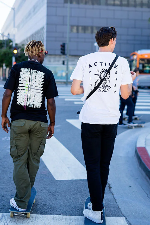 Two skaters in Active Ride Shop tees rolling across a city crosswalk