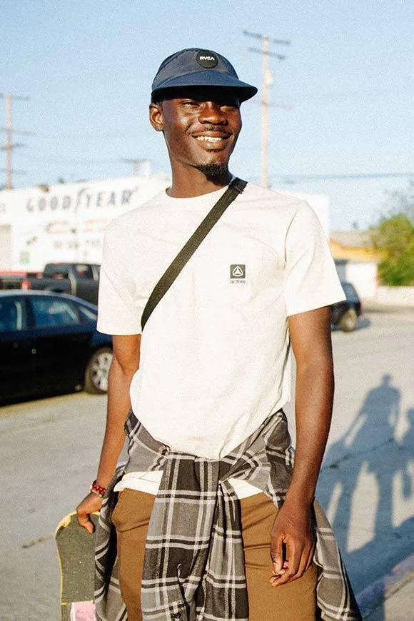 Smiling skater in a white Active pocket tee with a flannel tied at the waist