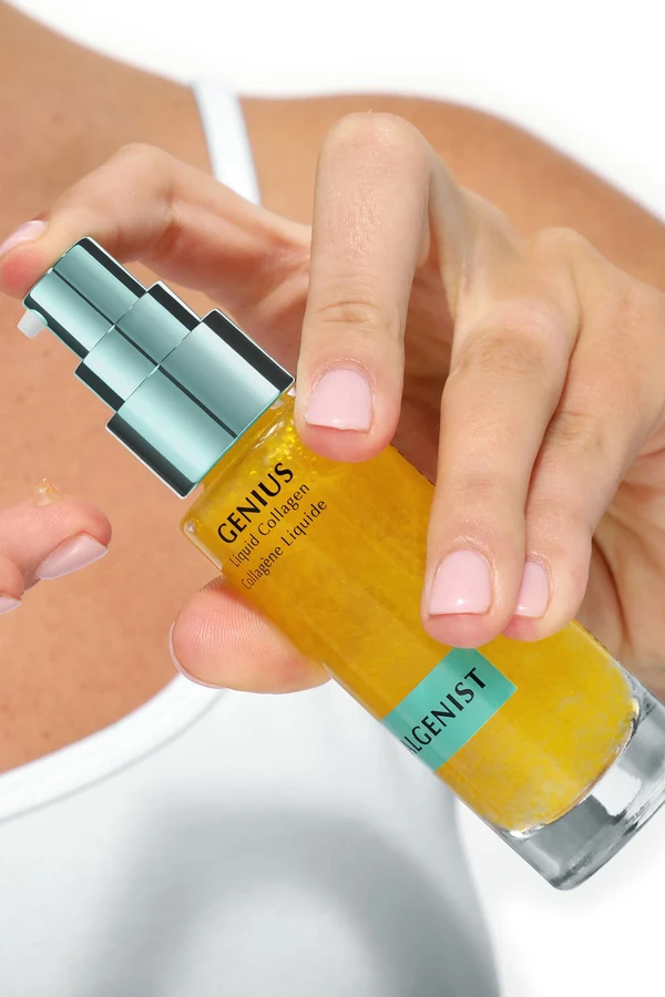 Hand pressing the pump on a bottle of Algenist GENIUS Liquid Collagen