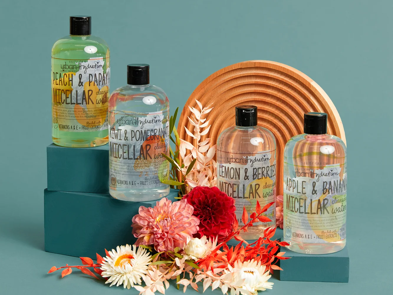 Four bottles of Urban Hydration micellar water on teal blocks with dried flowers