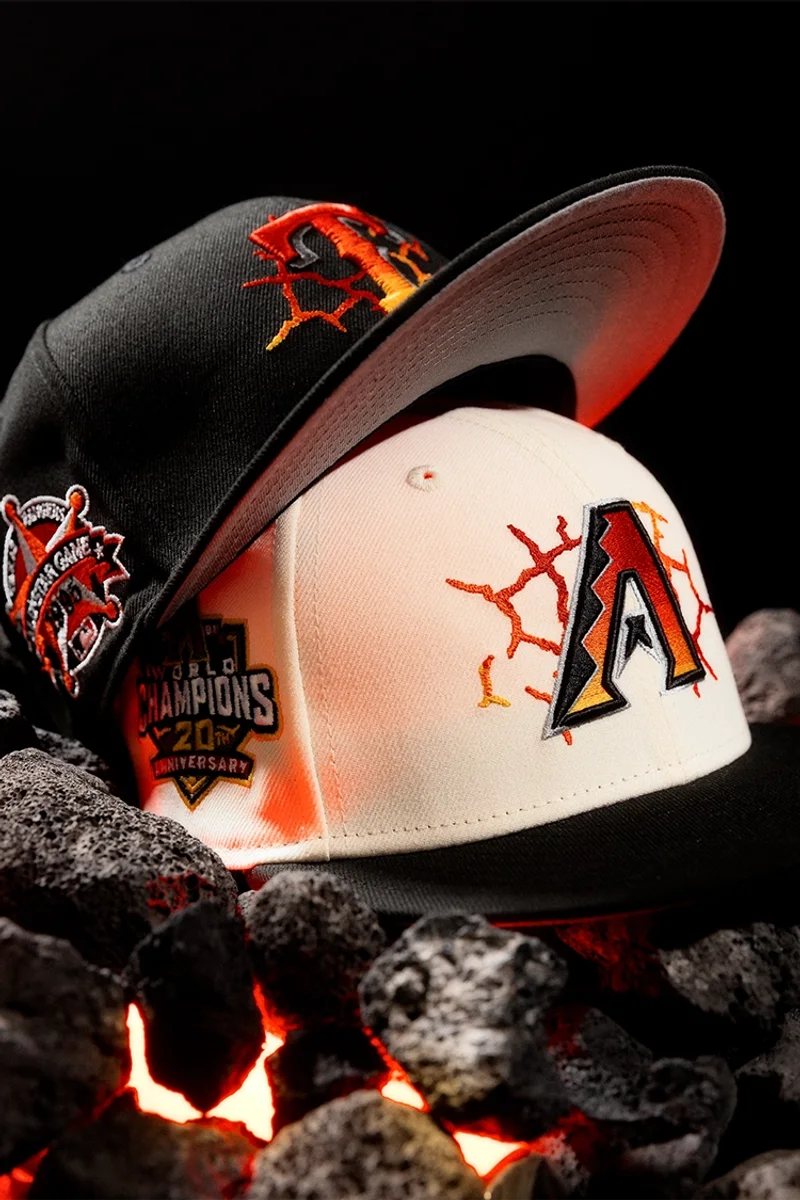 Two Hat Club Arizona Diamondbacks fitted caps, one black and one cream, on glowing lava rocks