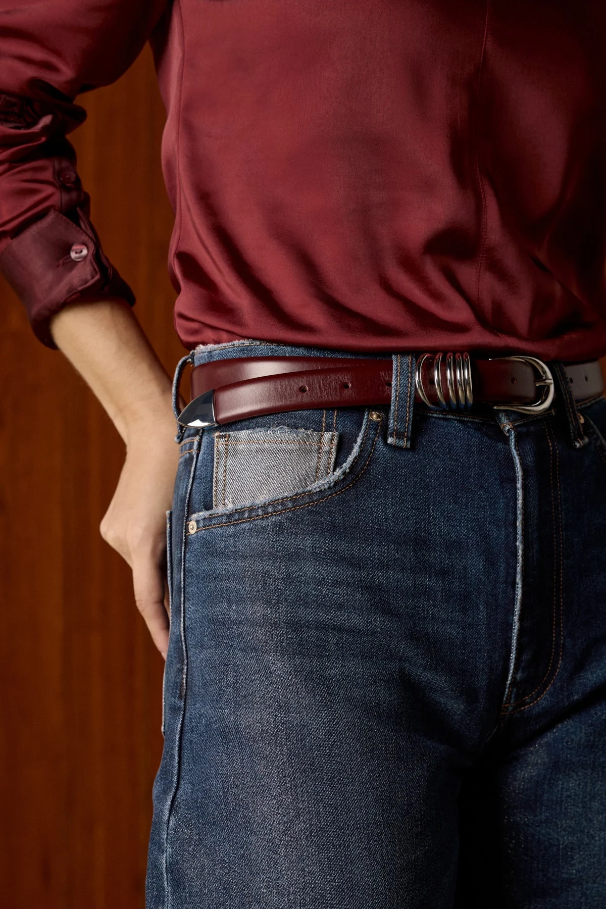 Close-up of dark Hudson jeans with a burgundy belt and silk shirt