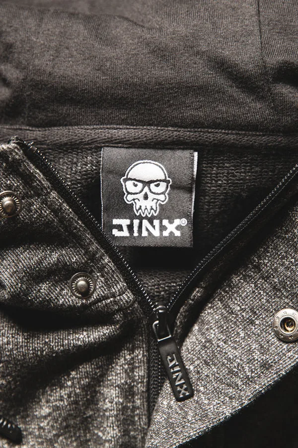 Close-up of a J!NX skull logo label inside a grey zip-up hoodie