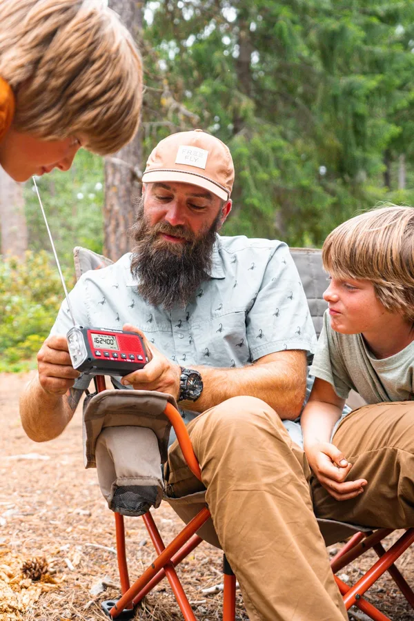 A family using a Midland emergency weather radio while camping