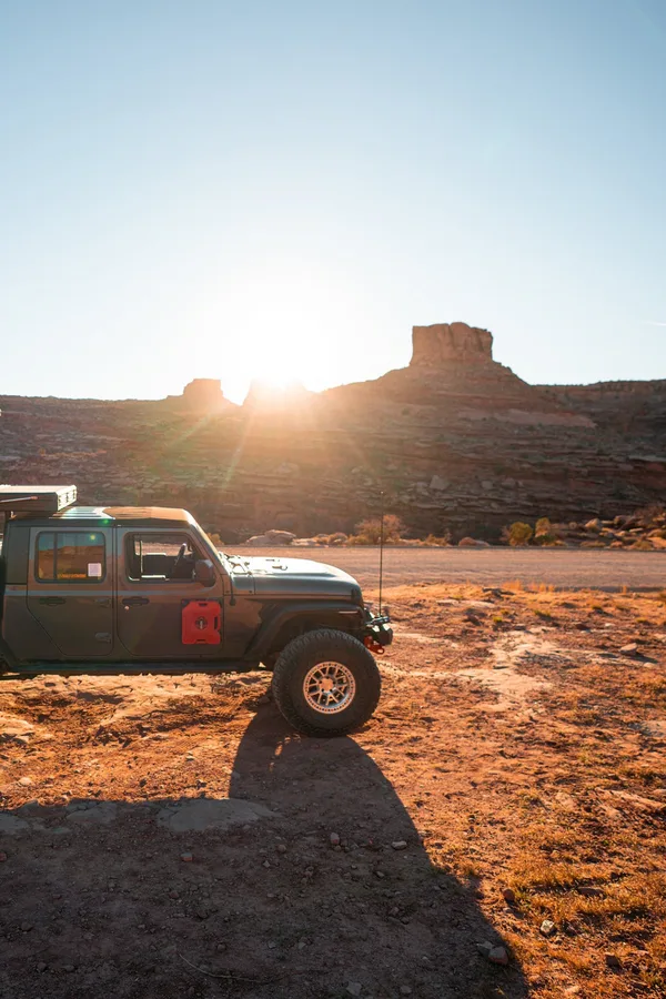 An overland adventurer atop a kitted-out truck at sunset