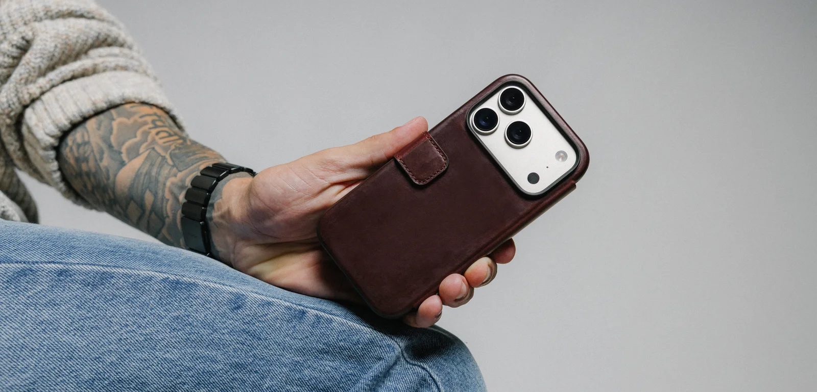Hand holding an iPhone in a brown leather Nomad folio case