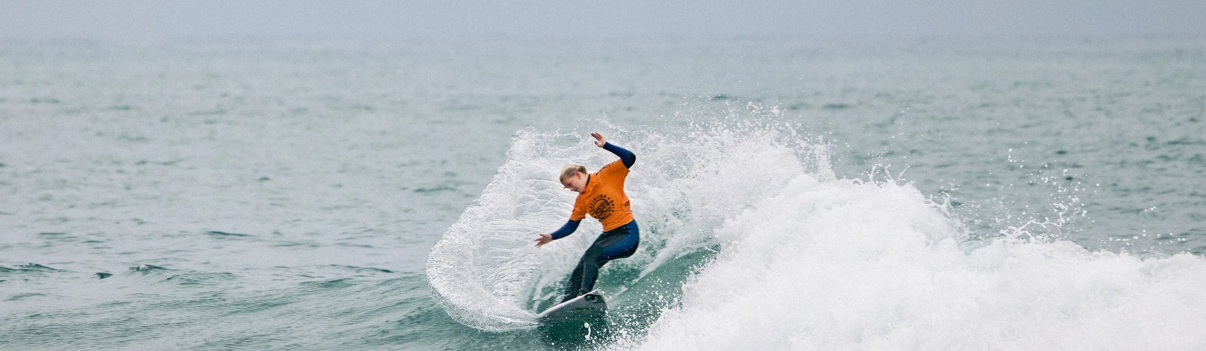 Surfer in an orange contest jersey carving a wave