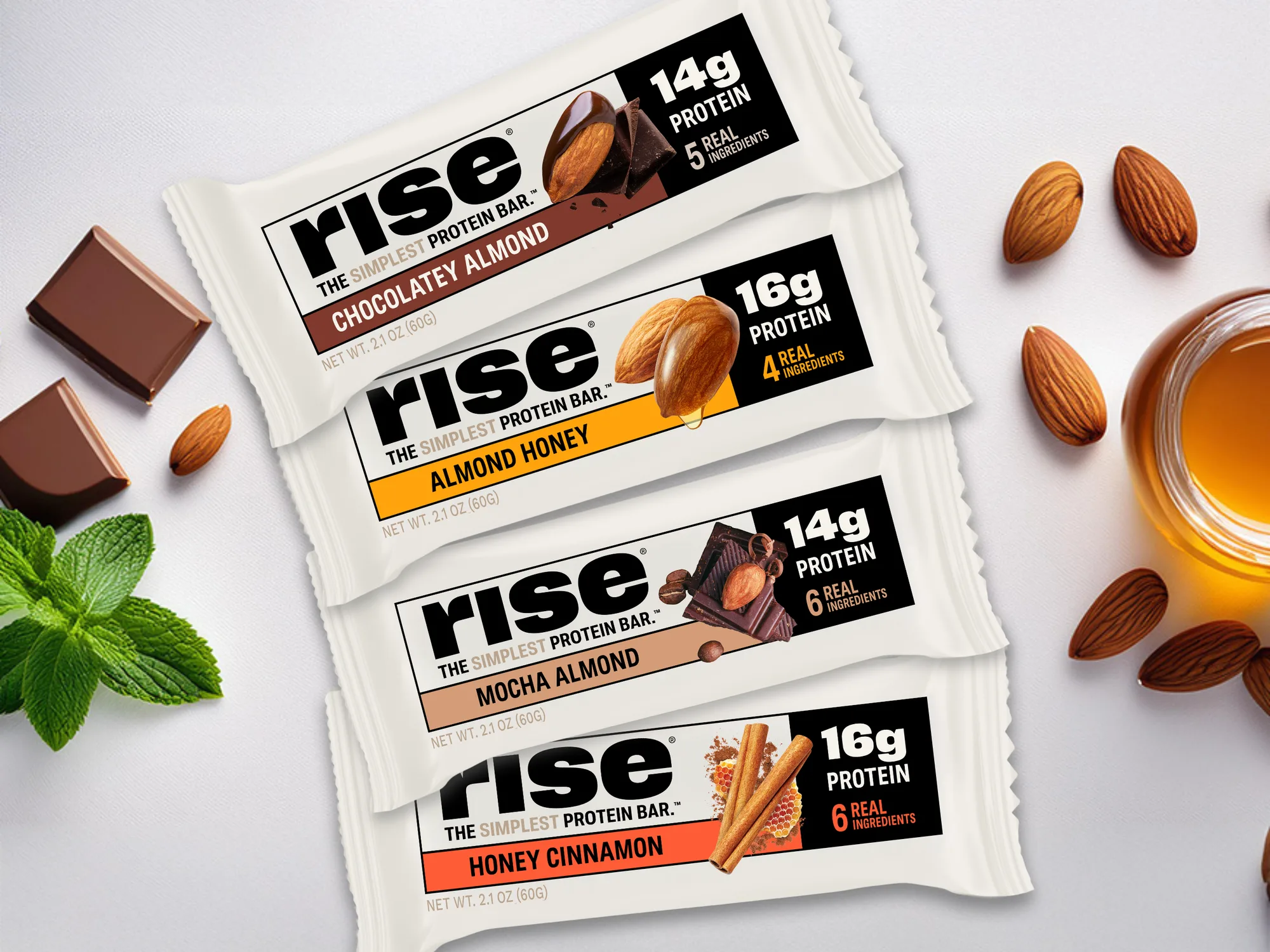 Four Rise Bar whey protein bars laid out with chocolate, almonds, mint and honey