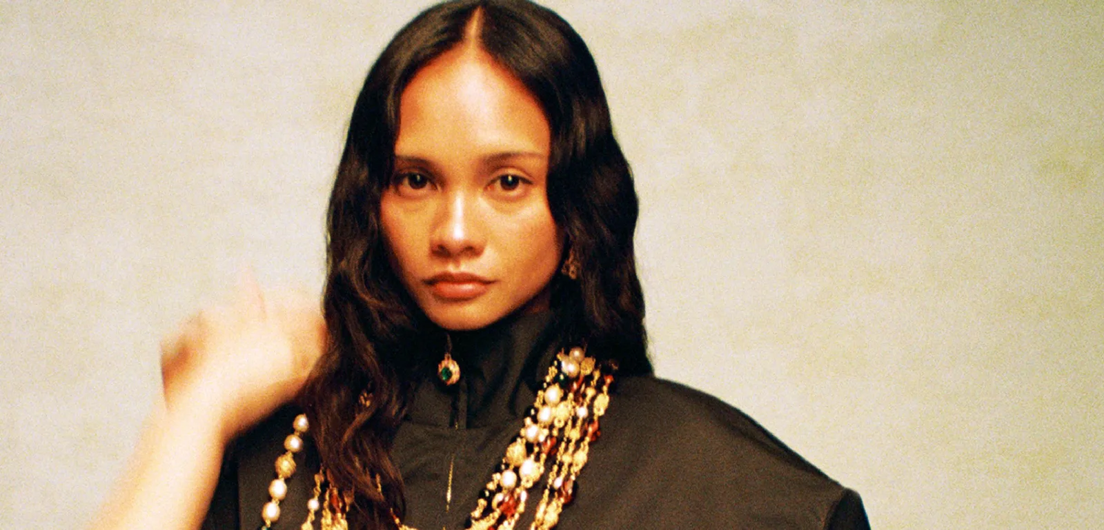 St. John campaign portrait of a woman in a black jacket with layered pearl and gold necklaces