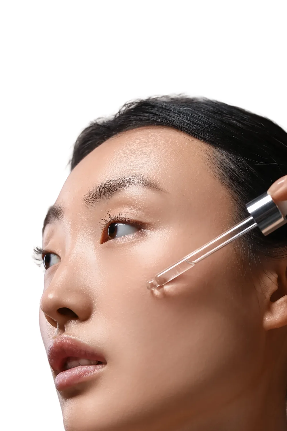Model applying a facial serum with a glass dropper